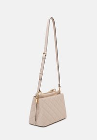 Beige, kviltet håndtaske med et struktureret design, der har en gyldent lynlås og justerbar skulderrem. Strukturmateriale i tekstureret kunstlæder.