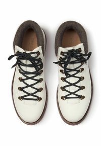 Scarpe da trekking in pelle bianca con lacci neri, dettagli marroni e un morbido bordo marrone scuro attorno al colletto. Suola testurizzata per una buona presa.