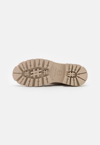 Beige Gummisohle mit tiefem Profil, diagonalen Rillen und leicht erhöhter Ferse. Markierungen umfassen ein Logo und die Größe 37.