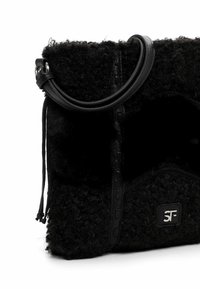 Borsa nera con una superficie testurizzata e soffice, manico arrotondato, bordi in pelle e un logo argentato che accentua il lato.
