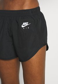 Pantalones cortos negros de Nike con una cinturilla elástica, con un logo blanco de "Nike Air" en el lado izquierdo, hechos de un material ligero y suave.