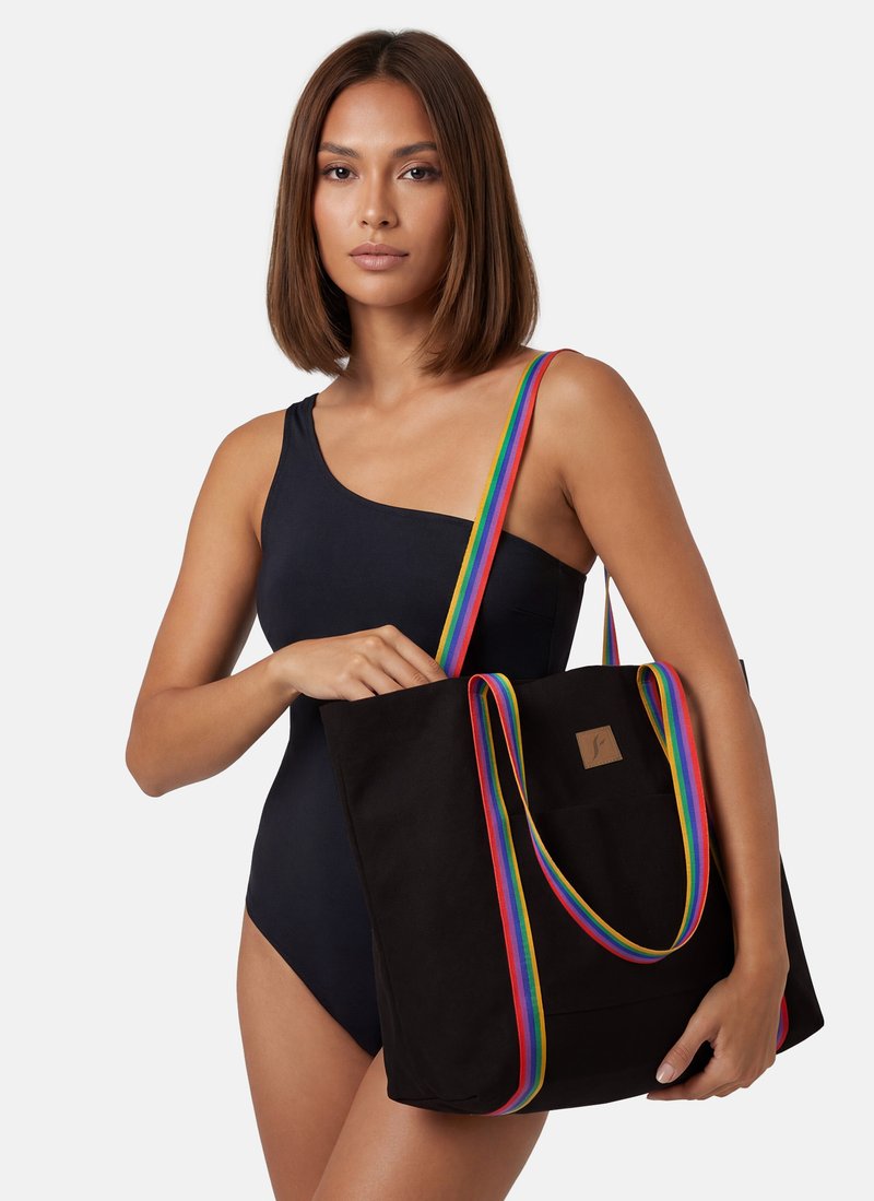 Czarna torba typu tote z teksturowanym wykończeniem, z kolorowym paskiem w tęczę i małą naszywką z logo z przodu.