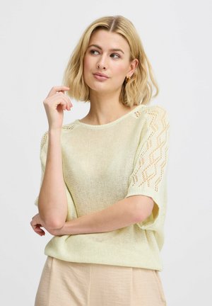 Lys gul strikket sweater med korte ærmer, der har et struktureret mønster på ærmerne. Blødt, åndbart materiale. Løs pasform.