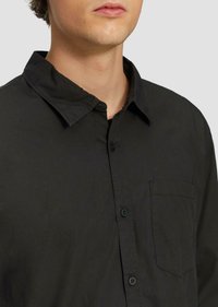 Zwarte button-up shirt met een kraag, voorzak en een gestructureerde stof. Bevat zwarte knopen en heeft een ontspannen pasvorm.