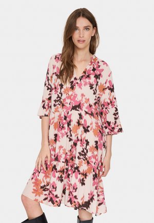Floral dress in light pink with black and orange accents. Features a V-neck, three-quarter sleeves, and a tiered hem. Made from soft fabric.