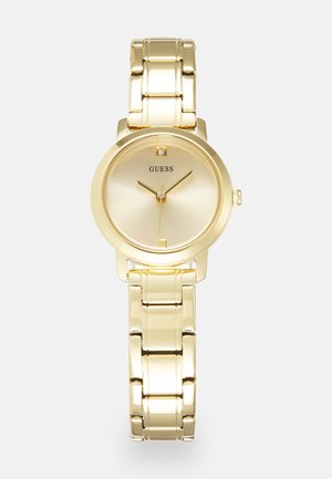 Zegarek na nadgarstek z metalową bransoletą w kolorze złotym, z okrągłą tarczą, minimalistyczną tarczą, jednym oznaczeniem diamentowym oraz logo "GUESS" na pozycji godziny 12.