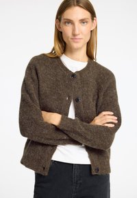 Braune, gestrickte Strickjacke mit rundem Kragen, langen Ärmeln und fünf schwarzen Knöpfen auf der Vorderseite; weicher Stoff mit einem leicht lockeren Schnitt.