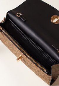 Sac à main en cuir marron texturé avec un intérieur en cuir noir, plusieurs emplacements pour cartes et une fermeture éclair et un fermoir dorés.