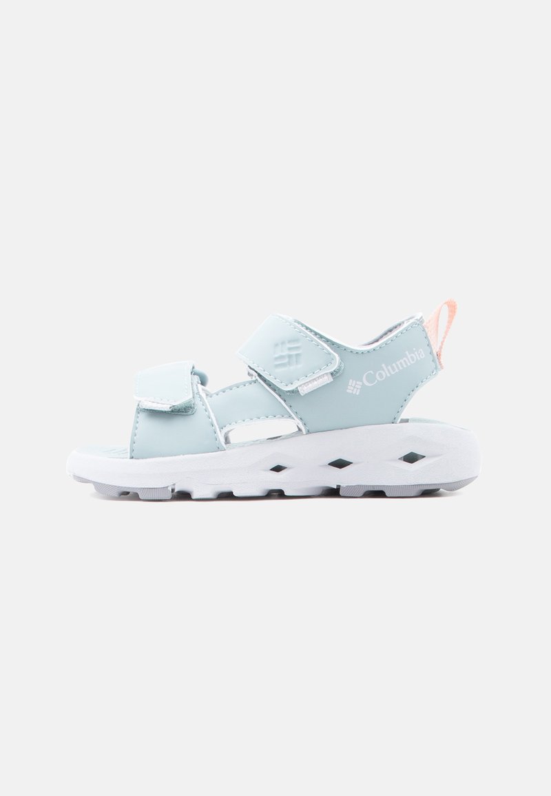 Ανοιχτό μπλε σανδάλι Columbia με ρυθμιζόμενους ιμάντες, μαλακή λευκή σόλα και ροδακινί λουράκι στη φτέρνα, σχεδιασμένο για άνεση και υπαίθρια χρήση.