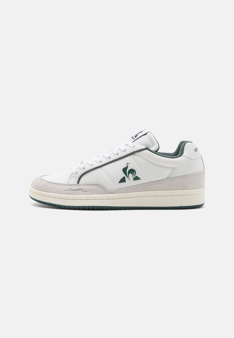 Fehér sneaker sima bőr felsőrészel, zöld részletekkel, velúr orral és krém színű gumitalppal. Az oldalsó panelem logó található.
