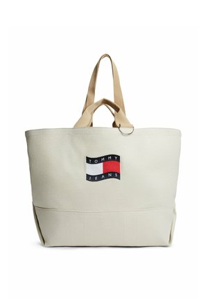 Sac fourre-tout Tommy Jeans beige avec des poignées beige et un patch logo à l'avant en rouge, blanc et bleu marine.