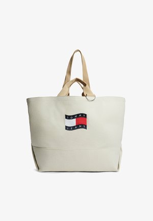 Beige Tommy Jeans Tragetasche mit beigen Griffen und vorderem Logo-Patch in Rot, Weiß und Marineblau.