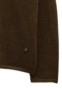 Brązowy sweter o fakturowanej strukturze, z prążkowanym wykończeniem i małą srebrną metką. Wykonany z miękkiego, dzianinowego materiału.