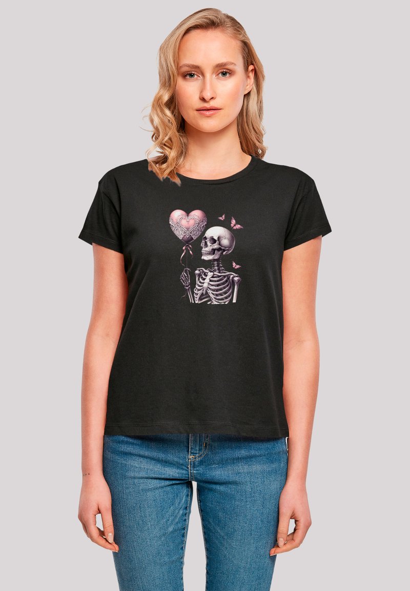 Black short-sleeve t-shirt featuring a skeleton holding a pink heart-shaped balloon, surrounded by pink butterflies. Soft cotton fabric.