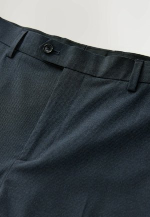 Pantalons bleu marine en tissu texturé, dotés d'une fermeture à un bouton et d'un devant plat. Un motif subtil ajoute de l'intérêt visuel.