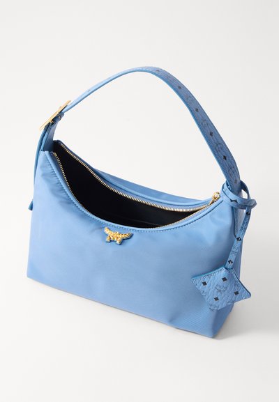 Blue nylon handbag with golden hardware, a zip closure, and a patterned strap. Features a decorative blue charm with a geometric shape.