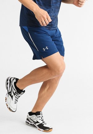 Mørkeblå atletikshorts med sideslids og lysegrå accenter, parret med sort-hvide sneakers med tekstureret design.