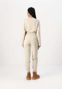 Sweatshirt beige et joggers en matériau doux, dotés d'une taille élastique et de poignets élastiques, associés à des bottines chelsea en daim marron.