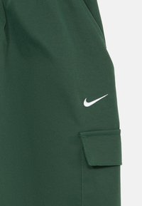 Zelene cargo kratke hlače iz trpežnega materiala, s stranskim žepom in majhnim belim Nike logotipom na levi strani.