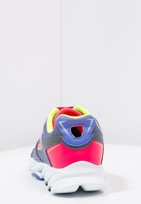 Chaussure de sport avec une tige en mesh gris, rose et accents jaune néon. Dotée d'un talon arrondi, de c ôtés texturés et d'une languette pour un enfilage facile.