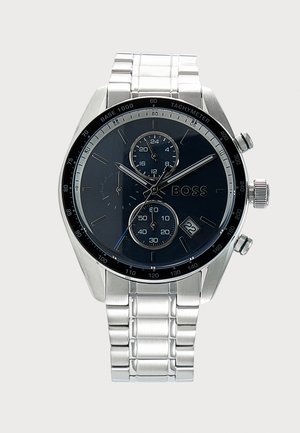 Montre-bracelet en métal argenté avec cadran noir, trois sous-cadrans, guichet de date, lunette tachymètre et marquage "BOSS" sur le cadran.