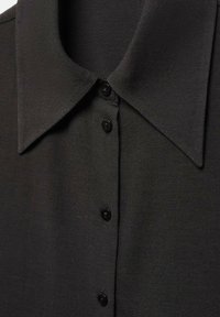 Zwarte collared shirt met een gladde stof, zes zwarte knopen aan de voorkant en een klassiek puntig kraagontwerp.