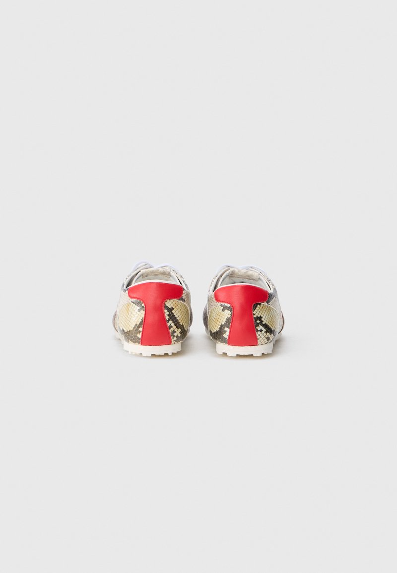 Et par low-top sneakers med slangeskindsmønster og rød hældetalje, set fra bagsiden på en hvid baggrund.