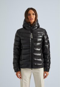 Giacca a vento nera con finitura lucida, chiusura con zip frontale e collo alto. Presenta dettagli con marchio e un design imbottito e aderente.