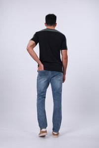 Camiseta negra con acentos verdes en los hombros, combinada con unos vaqueros de denim azul claro y zapatillas slip-on de color beige. Enfocándose en un ajuste casual y un diseño básico.