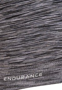 Harmaa kuviollinen urheiluvaatekangas pehmeällä, tekstuuripinnalla. Sisältää sanan "KESTÄVYYS" valkoisena, sijoitettuna alas laidan lähelle.