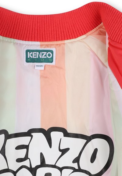 Giacca Kenzo Kids con collo a coste rosso, caratterizzata da un tessuto liscio e righe verticali pastello. Logo nero prominente all'interno.