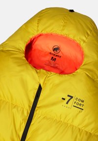 Żółta puchowa kurtka od wewnątrz z pomarańczowym podbiciem, czarnym zamkiem błyskawicznym i brandingiem Mammut. Rozmiar M oznaczony komfortową temperaturą -7°C.