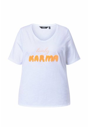 Biała, krótka koszulka z dekoltem w serek z nadrukiem "lovely KARMA", gdzie "lovely" jest napisane jasnym pismem a "KARMA" teksturowanymi pomarańczowymi literami.