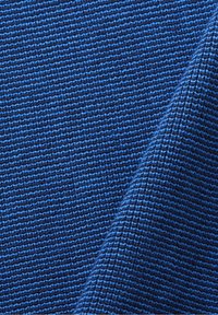 Texturerad blå tyg som visar ett strukturerat vävmönster, med växlande nyanser av blått och mörkblå ränder. Slät yta.