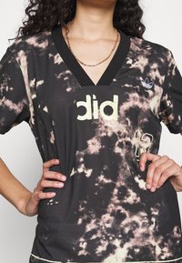 Svart kortärmad skjorta med tie-dye-mönster, med V-halsringning, tryckt "did" och "12" i gult, samt en liten blå logotyp.