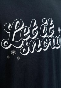 Navyblauwe katoenen t-shirt met vetwitte cursieve tekst "Laat het sneeuwen" en kleine sneeuwvlokontwerpen boven en onder de tekst.