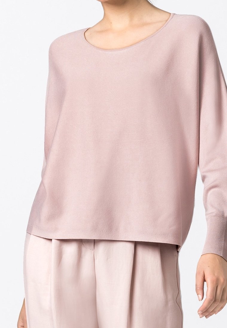 Pull en tricot rose clair avec un col rond, des manches longues et une coupe décontractée. Présente des détails de poignets côtelés et une texture lisse.