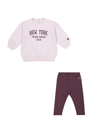Sudadera rosa clara con el texto "NEW YORK TEAM SINCE 1919", combinada con leggings morados oscuros que presentan un parche con el logo. Tejido suave, ajuste relajado.