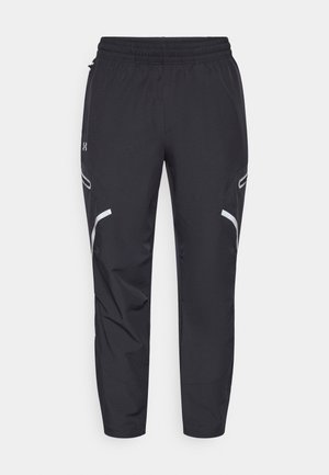Pantalon de sport noir en tissu léger, avec une taille élastique, deux poches latérales et des accents réfléchissants le long des coutures.