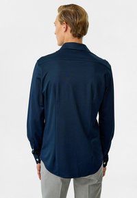 Marineblauwe longsleeve shirt met een gladde textuur, knoopmanchetten en een gebogen zoom. Voorzien van een klassieke kraag en een minimalistisch design.