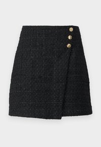 Fekete tweed mini szoknya strukturált szövettel, amely átkötős dizájnnal rendelkezik, és három aranyszínű gomb található az elülső részén a záráshoz.