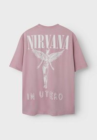 Rožinė medvilninė oversized marškinėlių su baltu angelo figūros grafiniu piešiniu ir tekstu "NIRVANA IN UTERO" ant nugaros. Trumpomis rankovėmis.