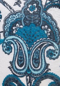 Textile with a floral pattern in shades of teal and navy on a light background. Features intricate detailing and textures in the design.