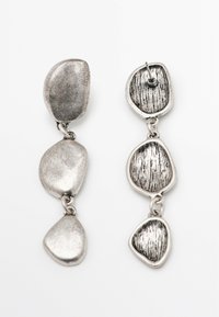 Orecchini pendenti in argento caratterizzati da tre elementi irregolari e texture. La superficie presenta una combinazione di finiture lisce e rigate.