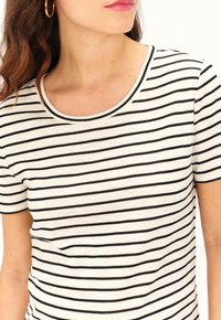 Camiseta de rayas en blanco y negro con cuello redondo y mangas cortas, hecha de una textura de tela suave. Sin patrones ni acentos visibles.