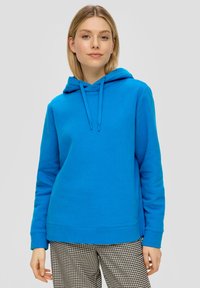Felle blauwe hoodie met een kangoeroezak, trekkoord capuchon en geribbelde manchetten. Draag over zwart-witte broek met een patroon.