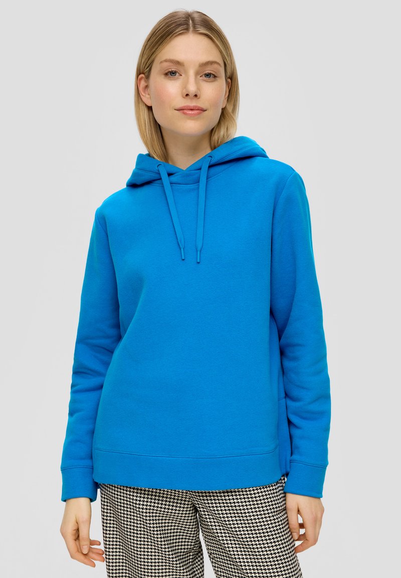 Felle blauwe hoodie met een kangoeroezak, trekkoord capuchon en geribbelde manchetten. Draag over zwart-witte broek met een patroon.