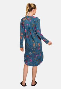Long-sleeve dress in blue fabric, featuring colorful floral embroidery, relaxed fit, hip-length, and side slits for added movement.