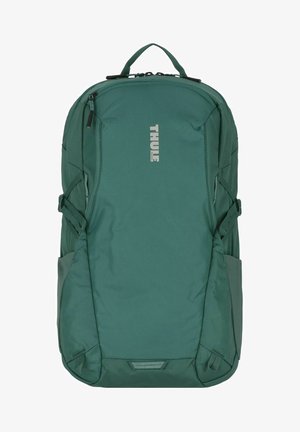 Zaino Thule di colore verde scuro, realizzato in tessuto resistente, con spallacci laterali regolabili, compartimenti con zip e una maniglia superiore.