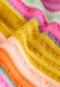 Tissu tricoté coloré à texture côtelée présentant des rayures horizontales dans des tons de jaune, rose, orange, vert et bleu.